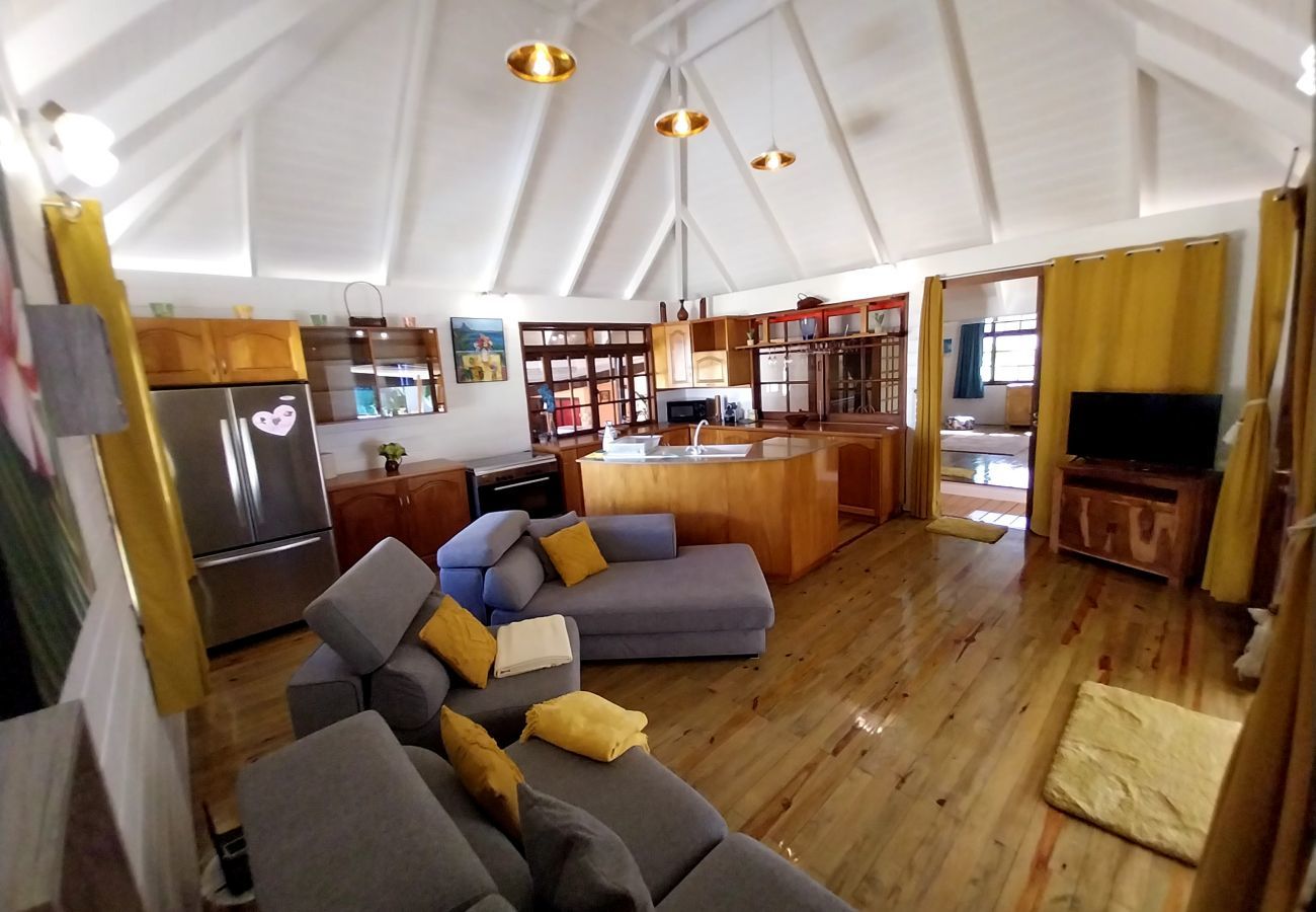 Wohnzimmer mit Sofa und Fernseher, Zugang zur Küche und Terrasse.