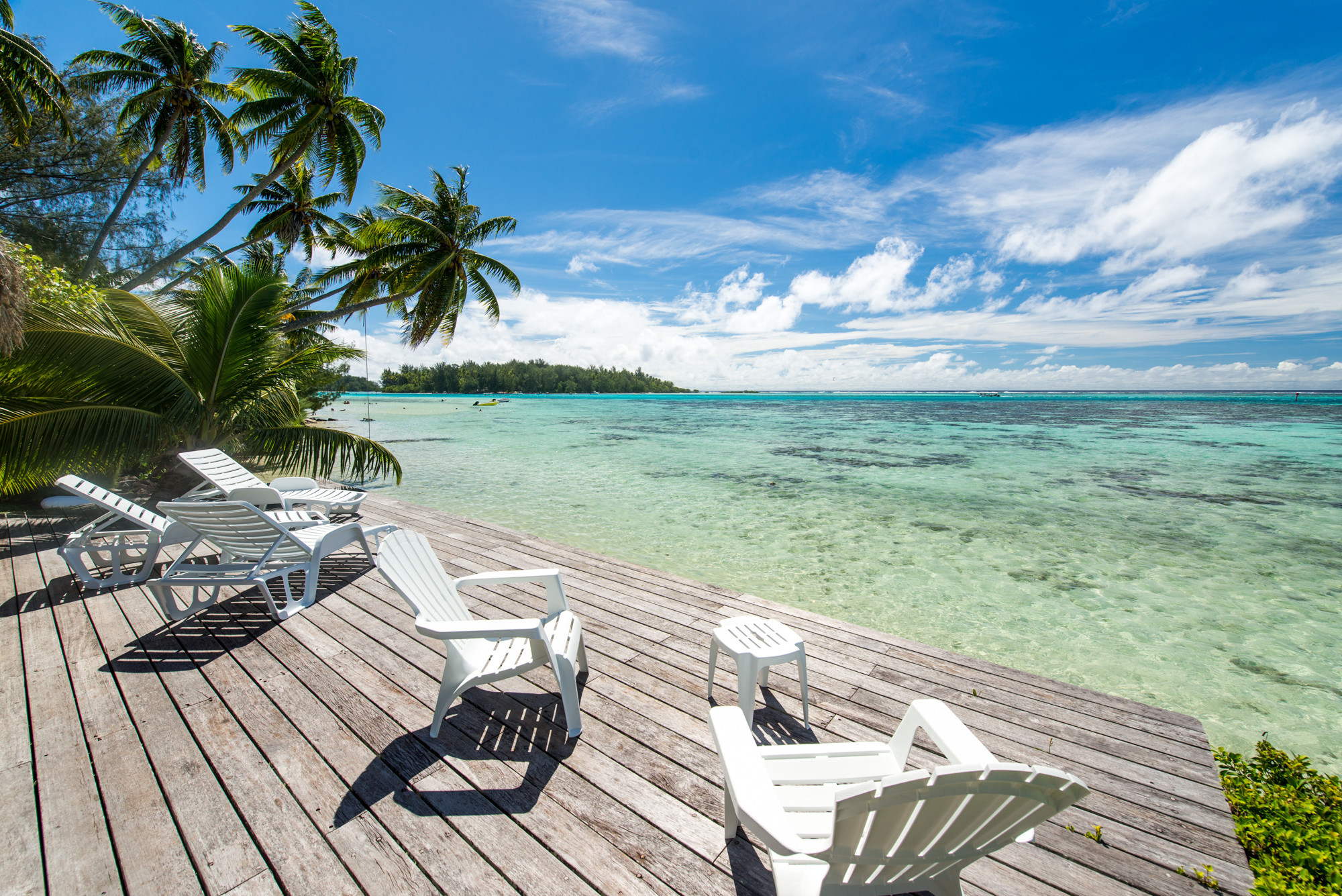 Deck au bord du lagon turquoise de Moorea avec transat pour se prélasser au soleil avec Fare pote'e derrière